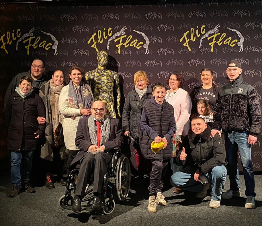 12 Personen stehen bzw. sitzen vor einer Wand mit der Aufschrift "FlicFlac"