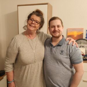 Mann und Frau stehen lächelnd Arm in Arm im Wohnzimmer.