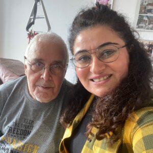 Frau mit langen, gelockten Haaren und Brille und Mann mit Brille schauen in die Kamera