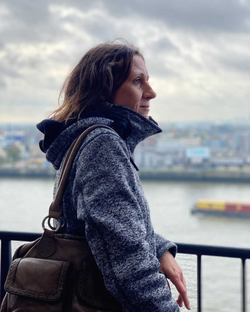 Seitenansicht einer Frau am Hafen mit Rucksack und blauer Jacke