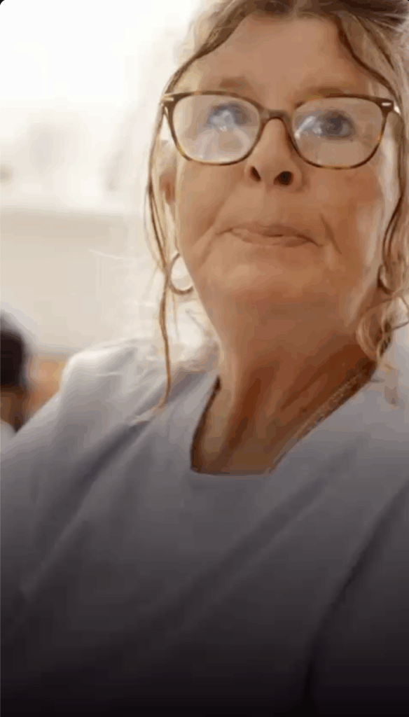 Nahaufnahme vom Gesicht einer Frau mit Brille, ihre Haare umspielen ihr Gesicht.