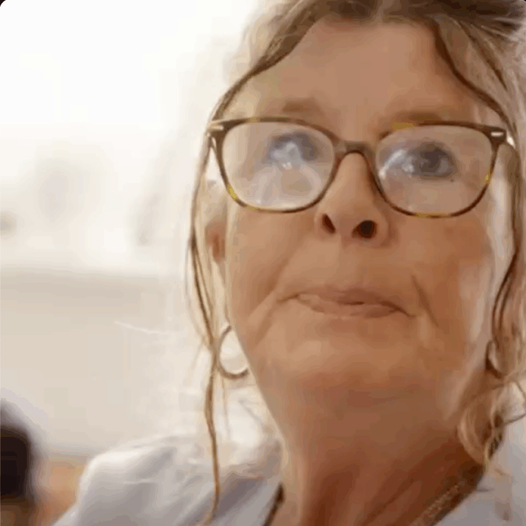 Nahaufnahme vom Gesicht einer Frau mit Brille, ihre Haare umspielen ihr Gesicht.