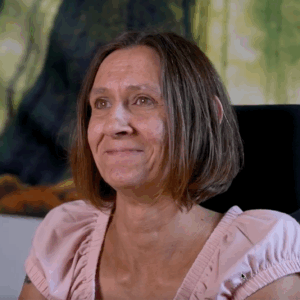 Frau mit braunem Bob und rosa Shirt lächelt an der Kamera vorbei