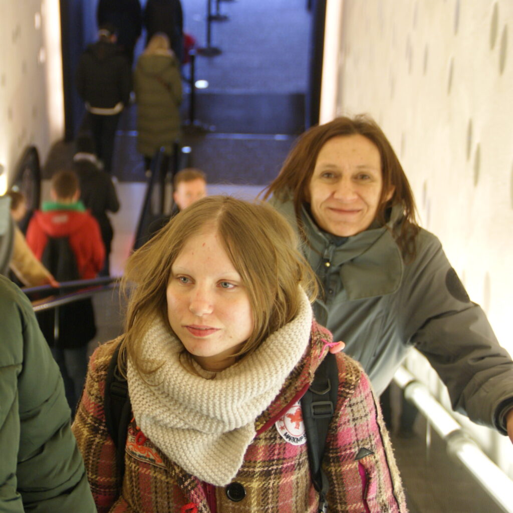 Drei Frauen auf einer Rolltreppe in warmer Kleidung