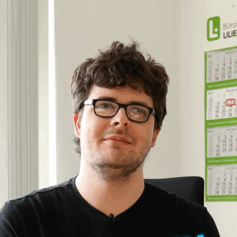 Portrait eines jungen Mannes mit kurzen dunklen Haaren, Brille und schwarzem Shirt