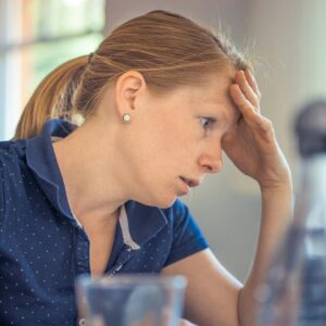 Frau stützt ihren Kopf auf der linken Hand ab und schaut überfordert.