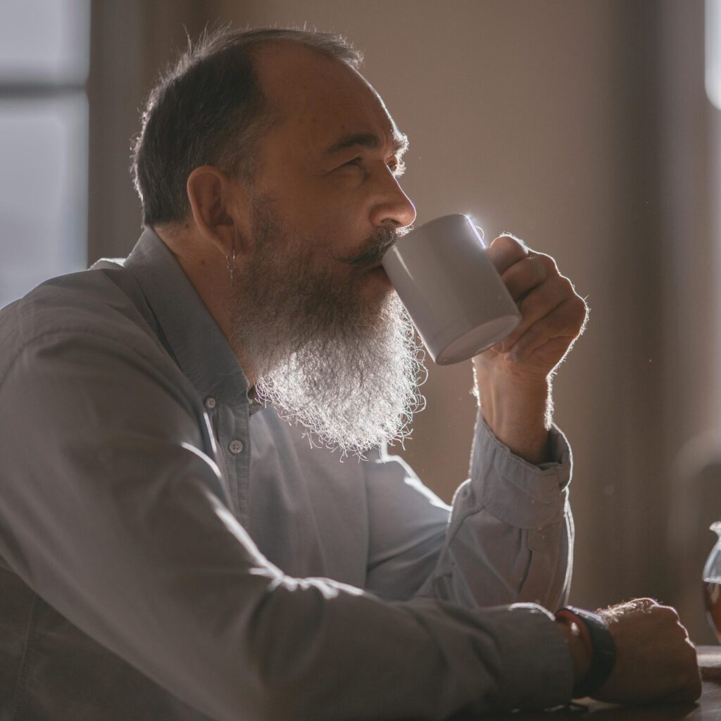 Mann mit langem weißen Bart trinkt aus einer Tasse