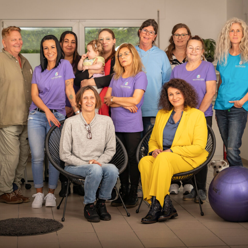 11 Personen und ein Baby sitzen und stehen für ein Gruppenbild zusammen.
