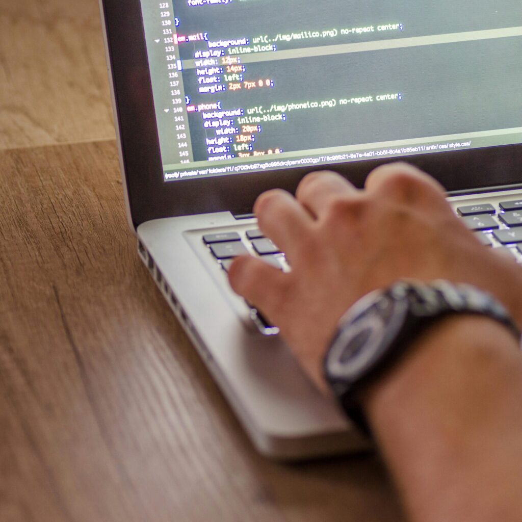 Hand tippt am Laptop mit Code