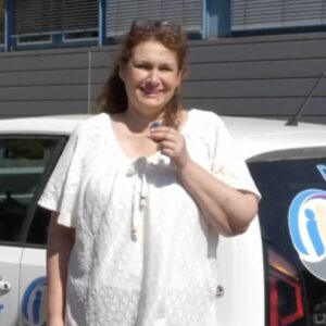 Frau Wagner Matthes steht vor einem weißen Auto mit "Deine Alltagsmeister" Logo